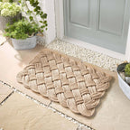 Rope beige door mat outside a green door with white pebbles