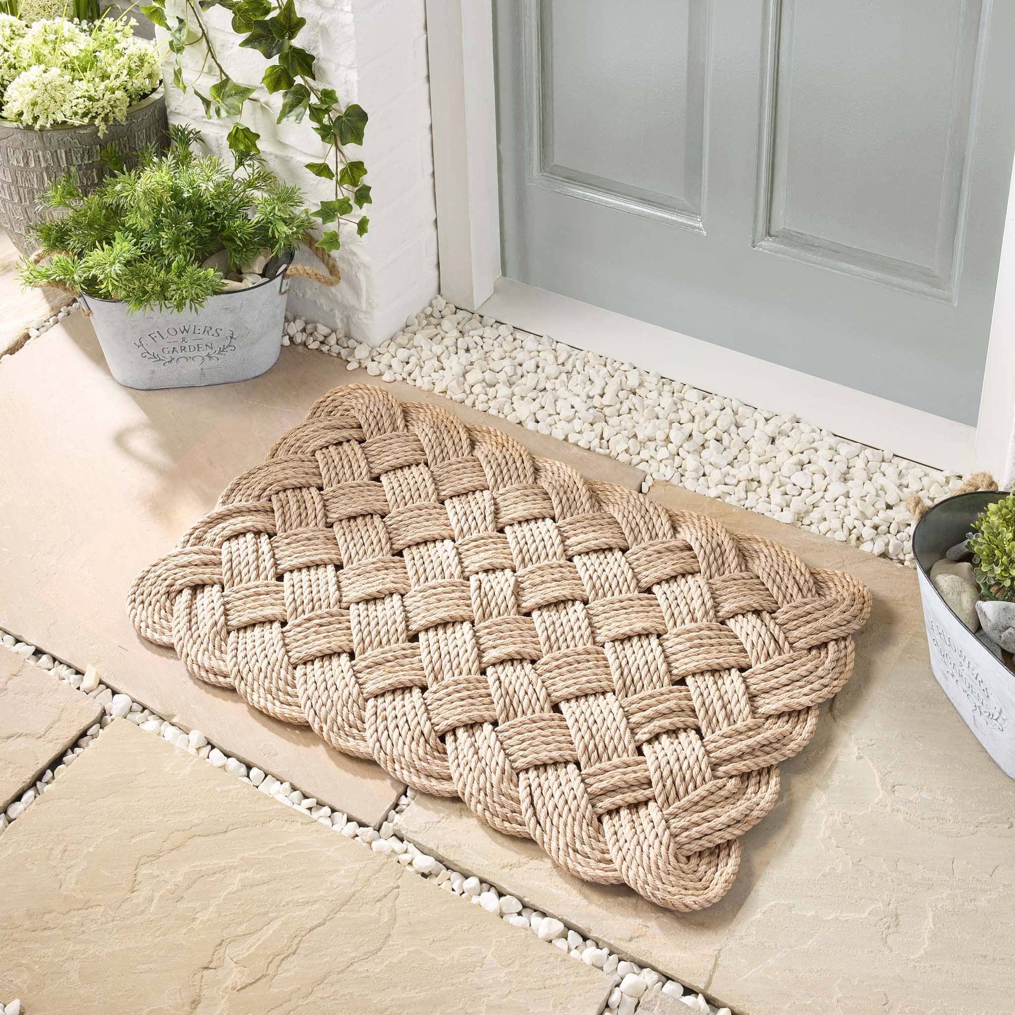 Rope beige door mat outside a green door with white pebbles
