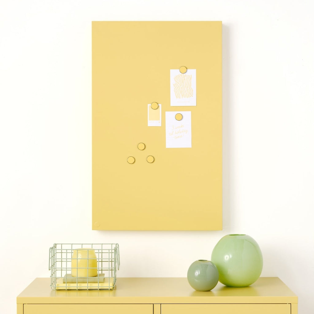 Yellow locker with a yellow bulletin board above it on a white wall.