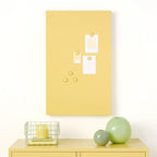 Yellow locker with a yellow bulletin board above it on a white wall.