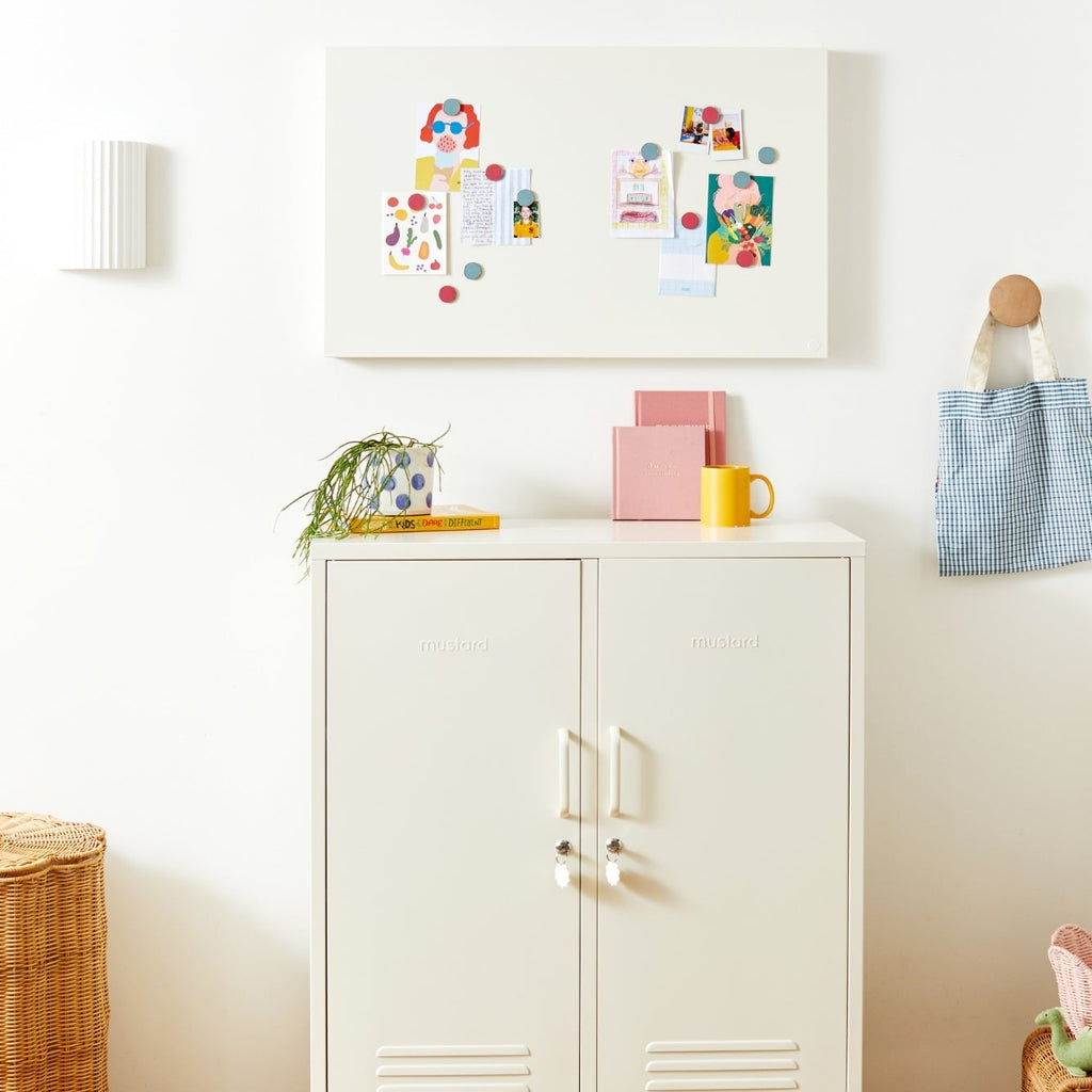 White cabinet with colorful decor items in a room with wooden floor and white walls.