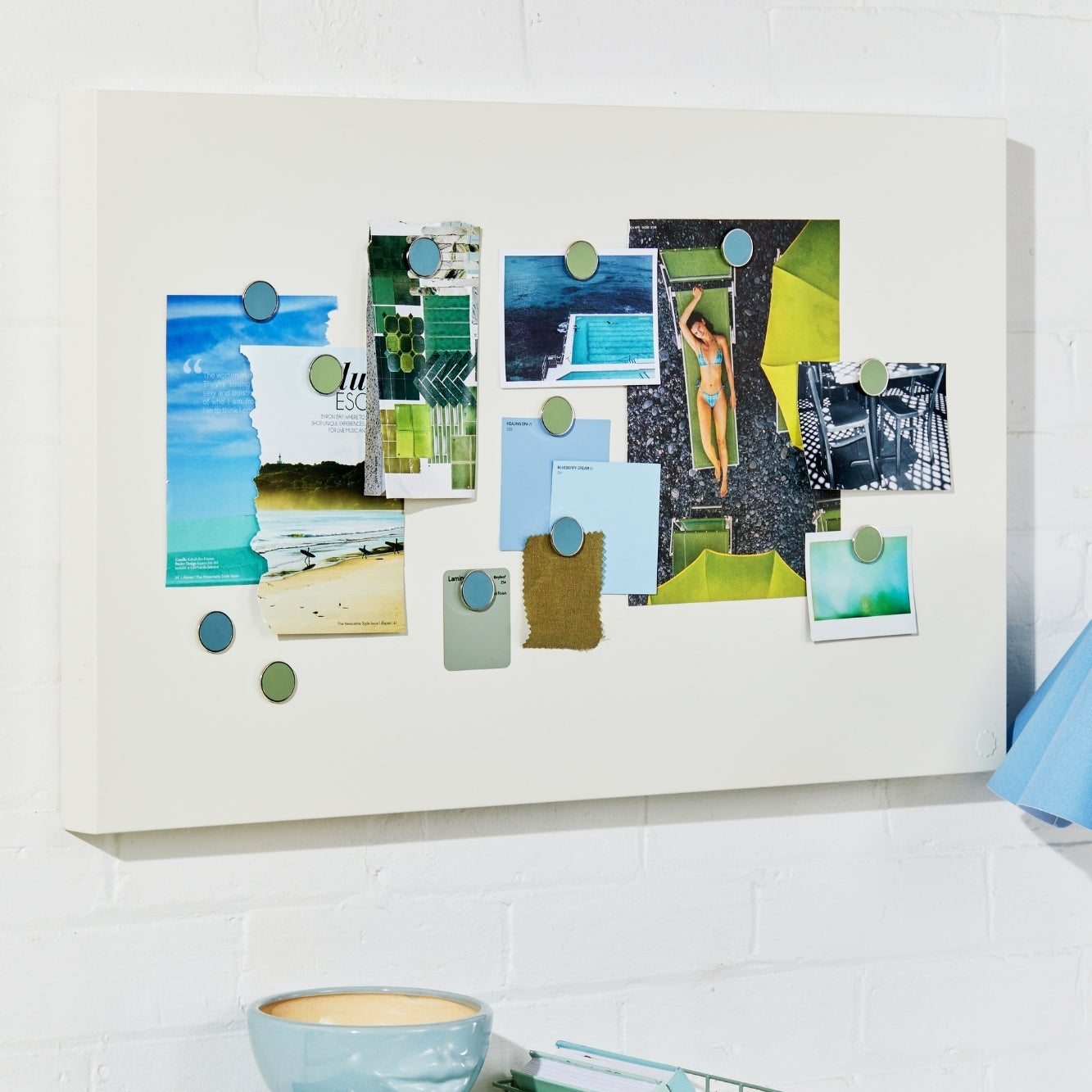 Desk with a decorative wall art piece, books, and a basket on a white tiled wall.