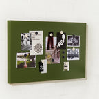 Green magnetic notice board with various photos and notes on a white wall