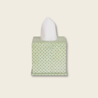 Green patterned tissue box cover with a white tissue on a beige background