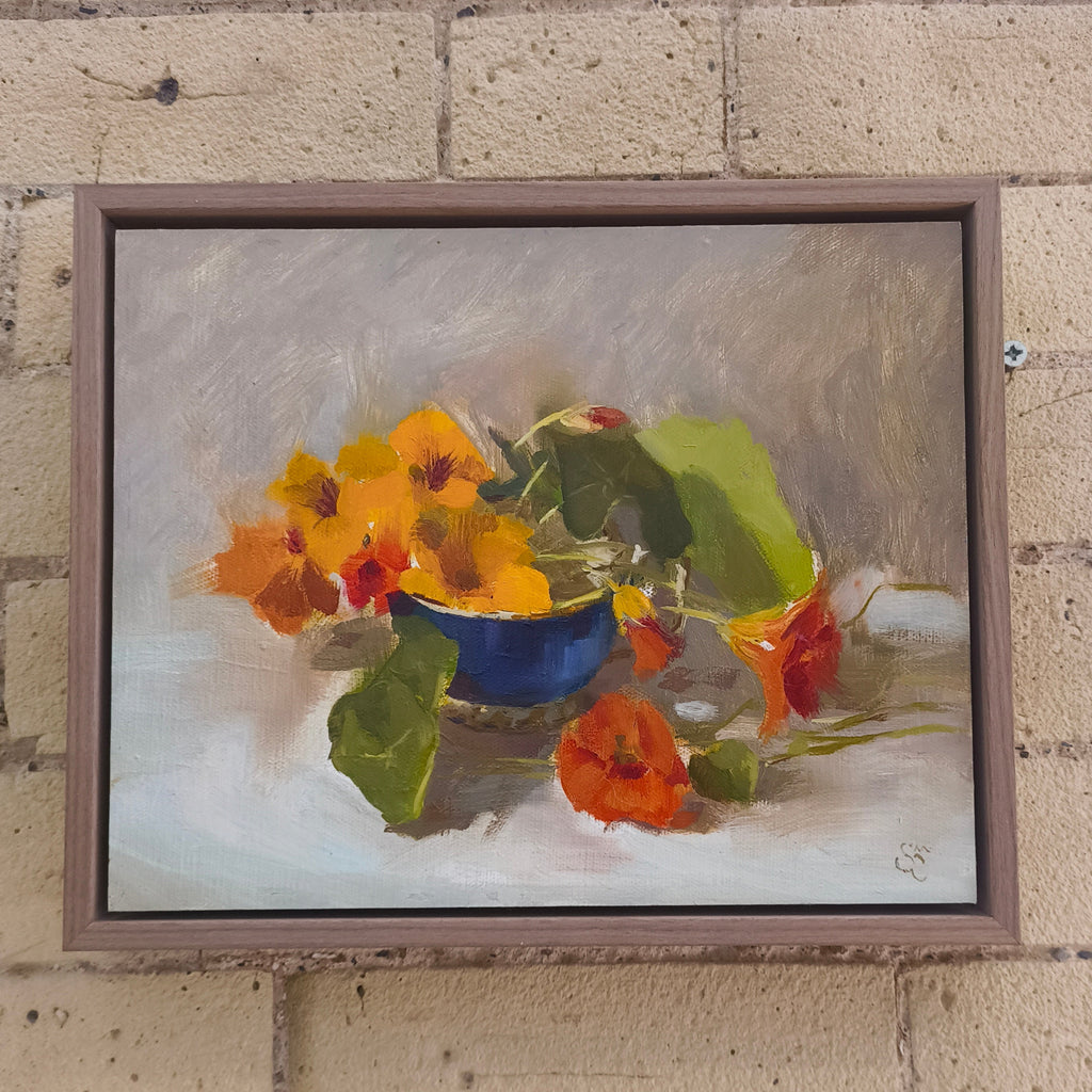 Framed painting of a still life with flowers on a brick wall