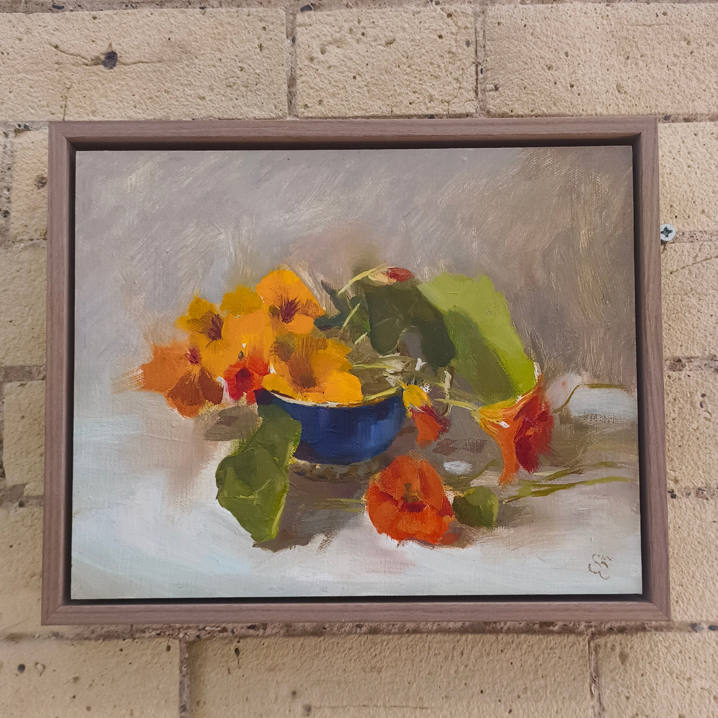 Framed painting of a still life with flowers on a brick wall