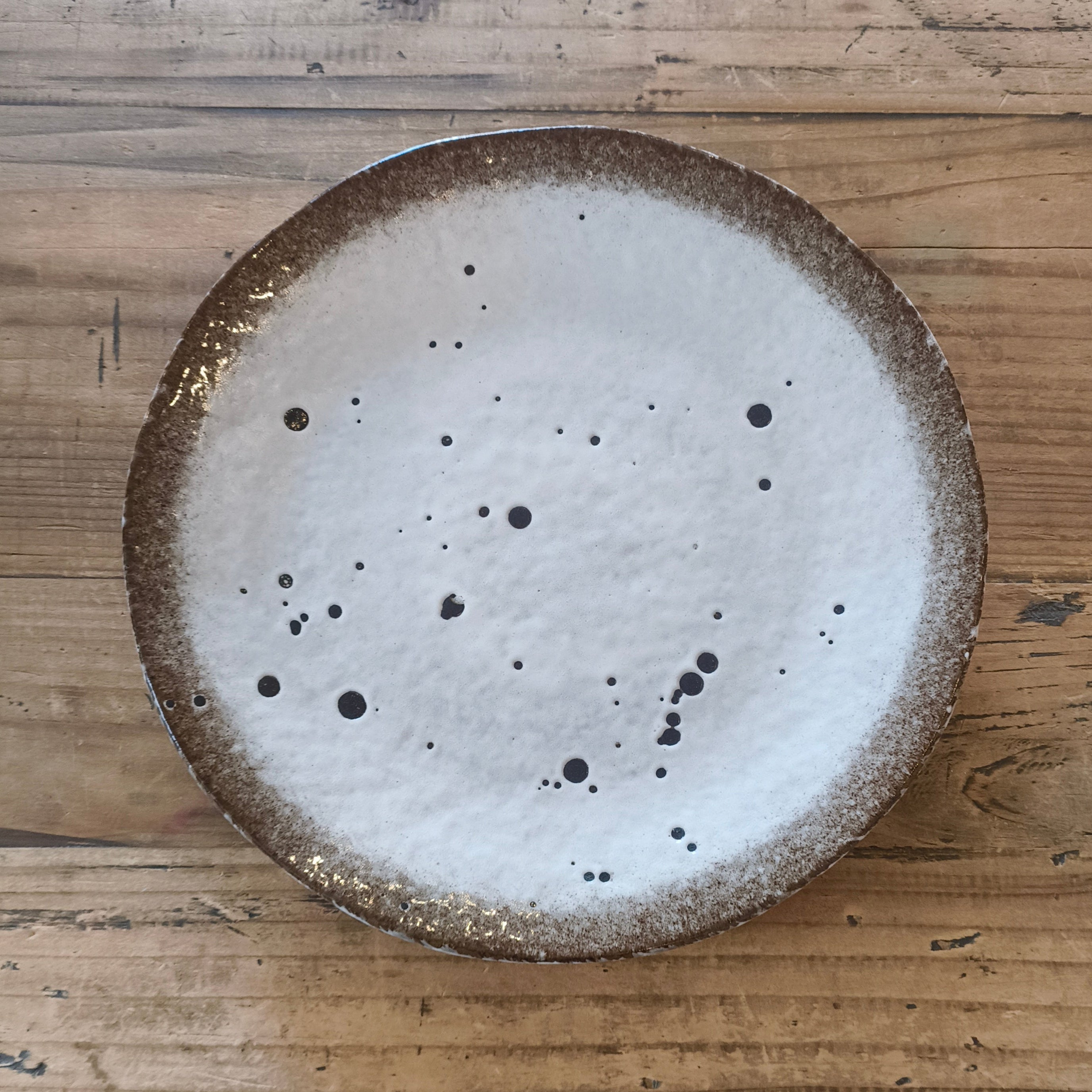Round ceramic plate with a textured surface on a wooden floor
