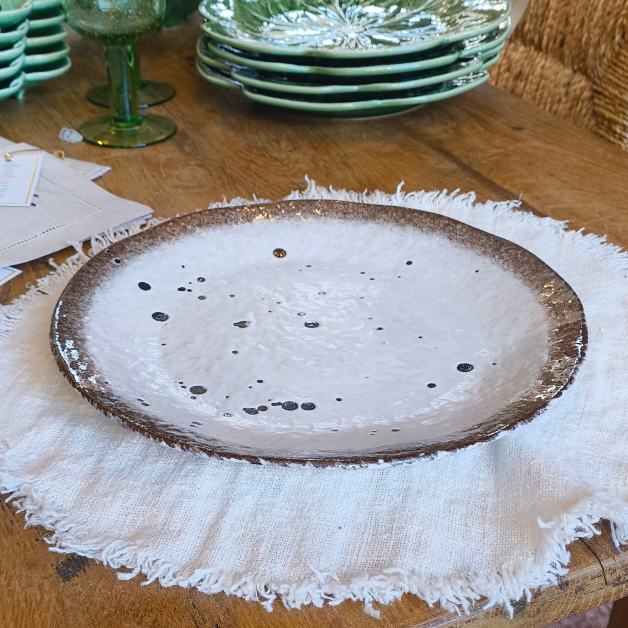 Vintage wooden table with ceramic plates and green glassware on a textured surface.