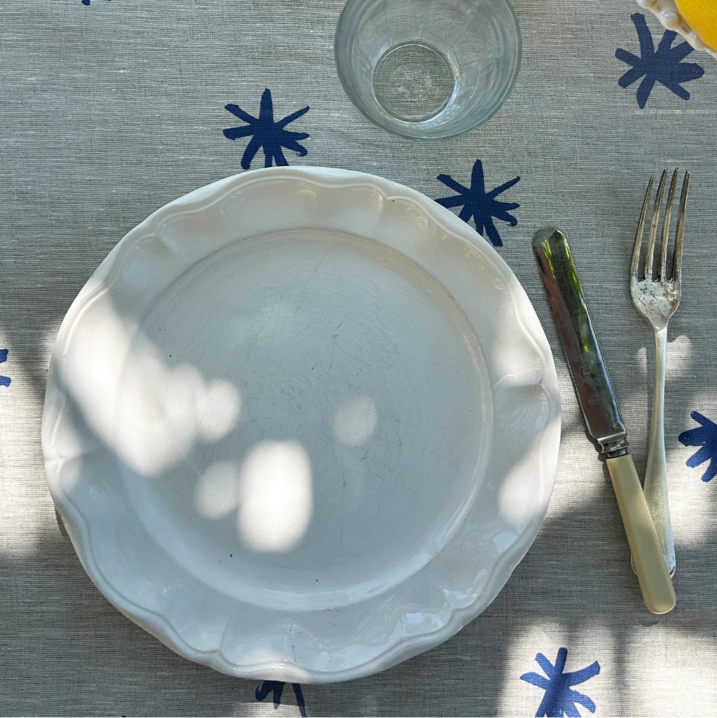 White plate on a tablecloth with blue star patterns, accompanied by a glass, knife, and fork.