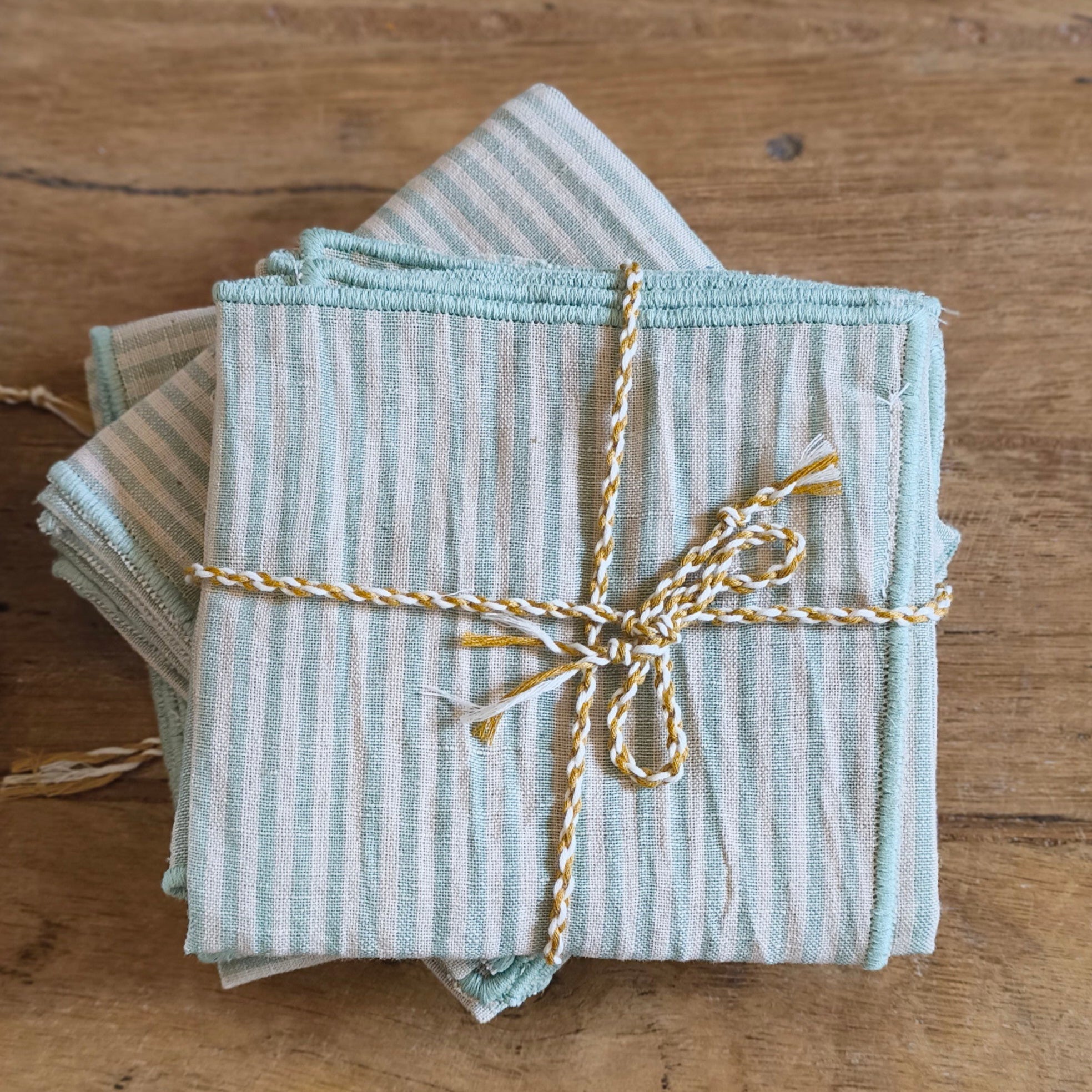 stripe blue and green cotton napkins tied with a string on a wooden table