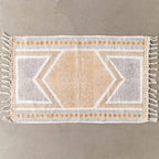 Textile with geometric pattern and tassels on a plain background