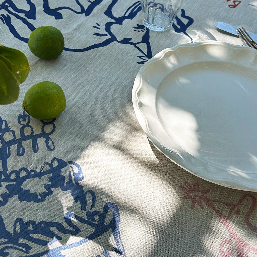 Table setting with a white plate, glass, and green apples on a patterned tablecloth.