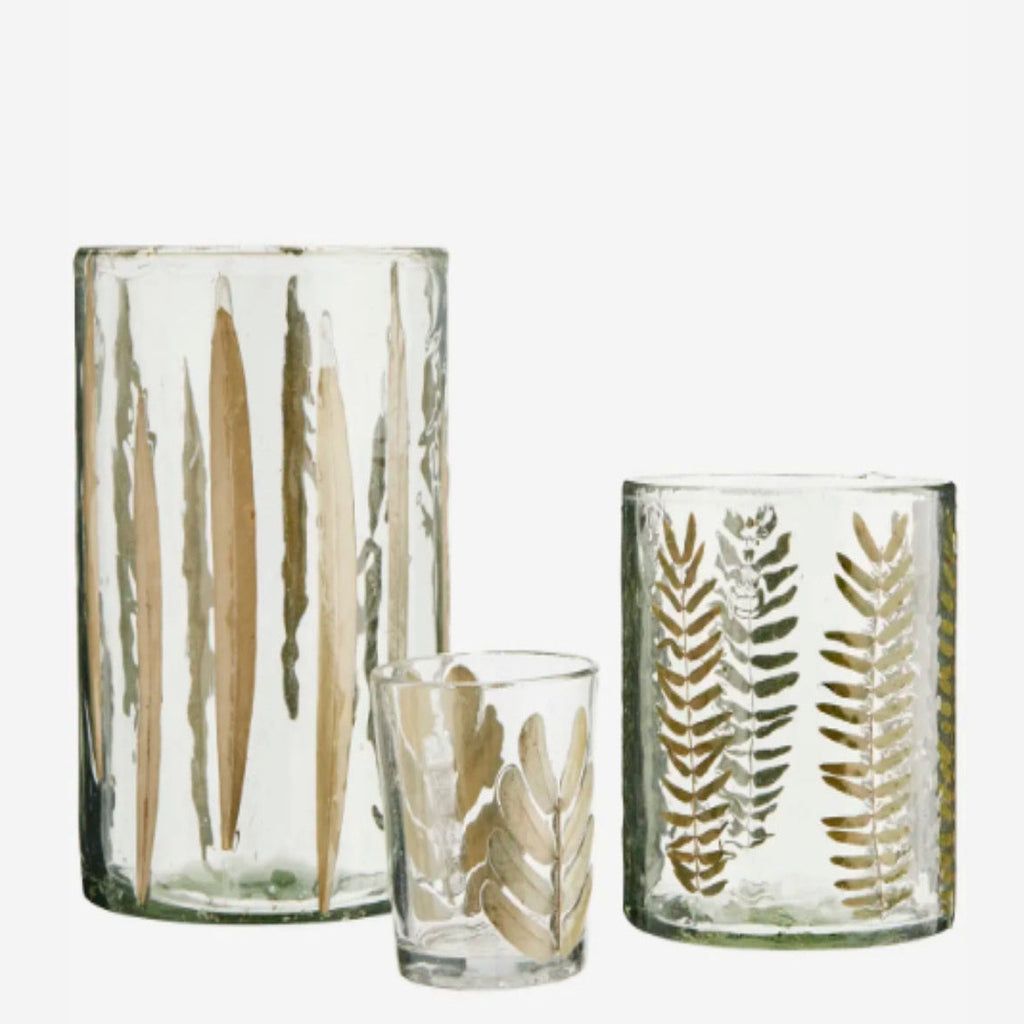 Set of three glass tumblers with leaf patterns on a white background