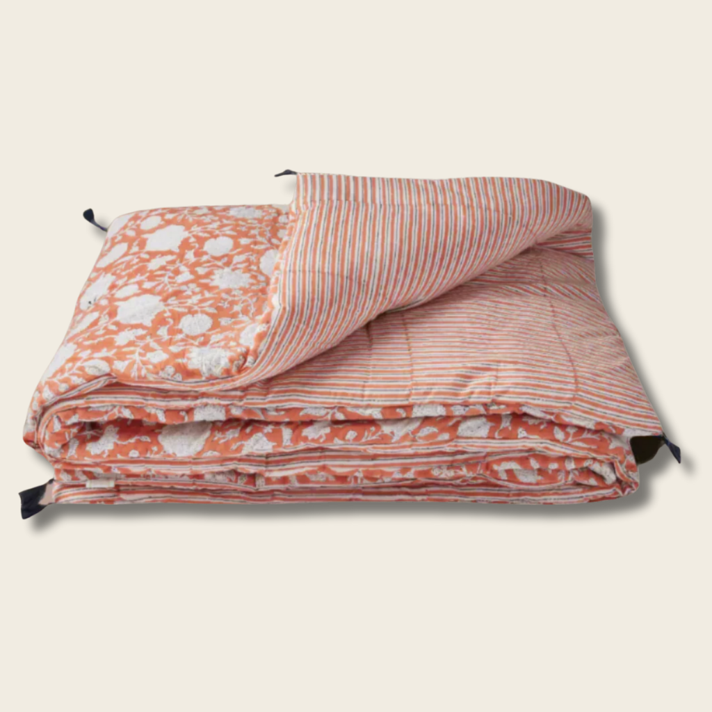 Folded quilt with floral and striped patterns on a beige background