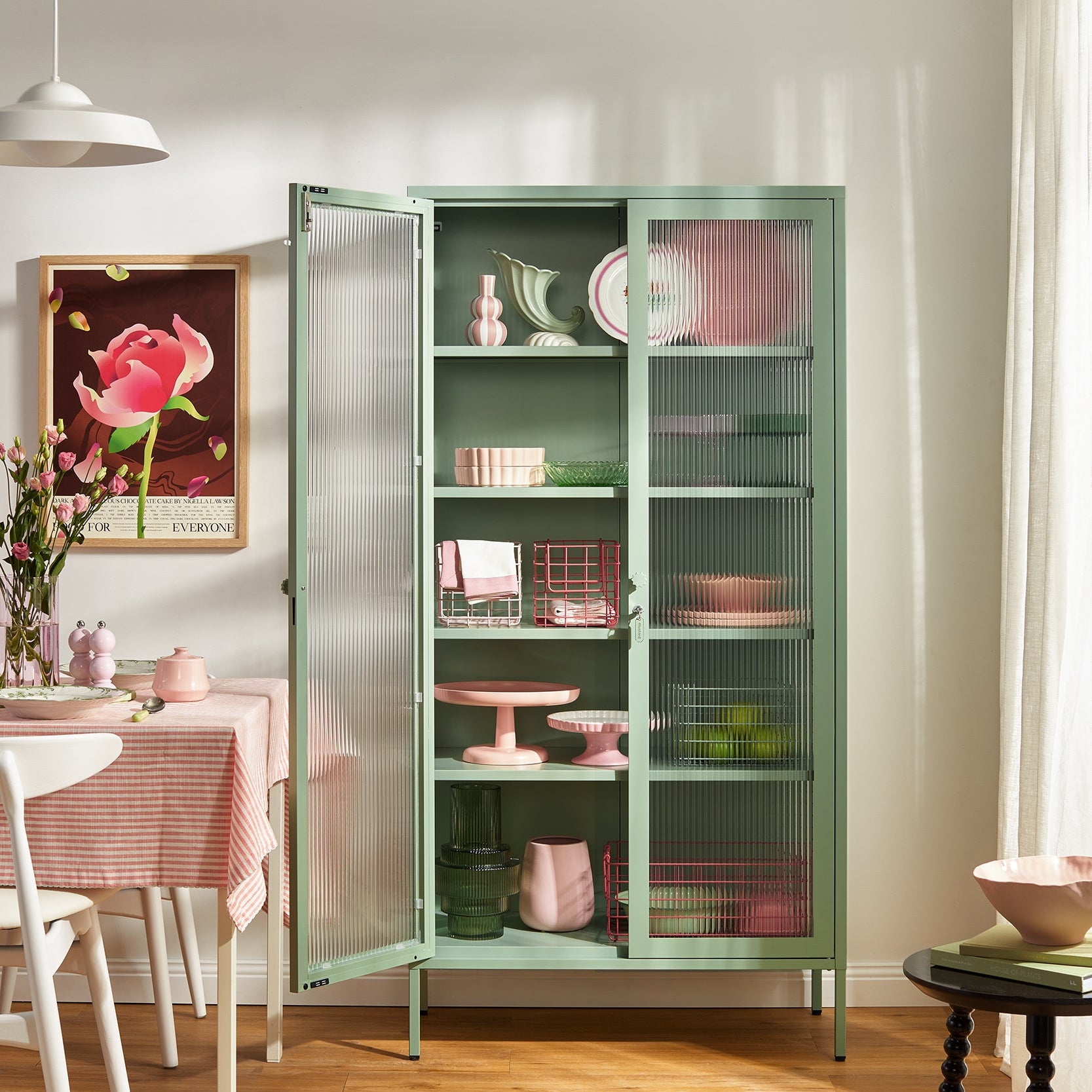 Green glass-fronted cabinet in a room with a table and chairs.