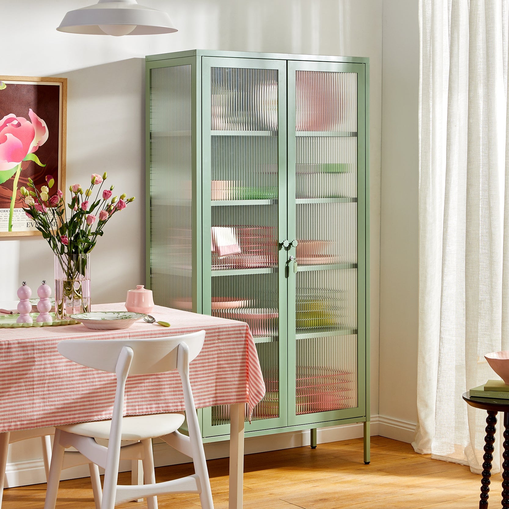 Light green glass cabinet with pink interior in a room with a table and chairs.