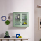Green cabinet on a white wall with decorative items around
