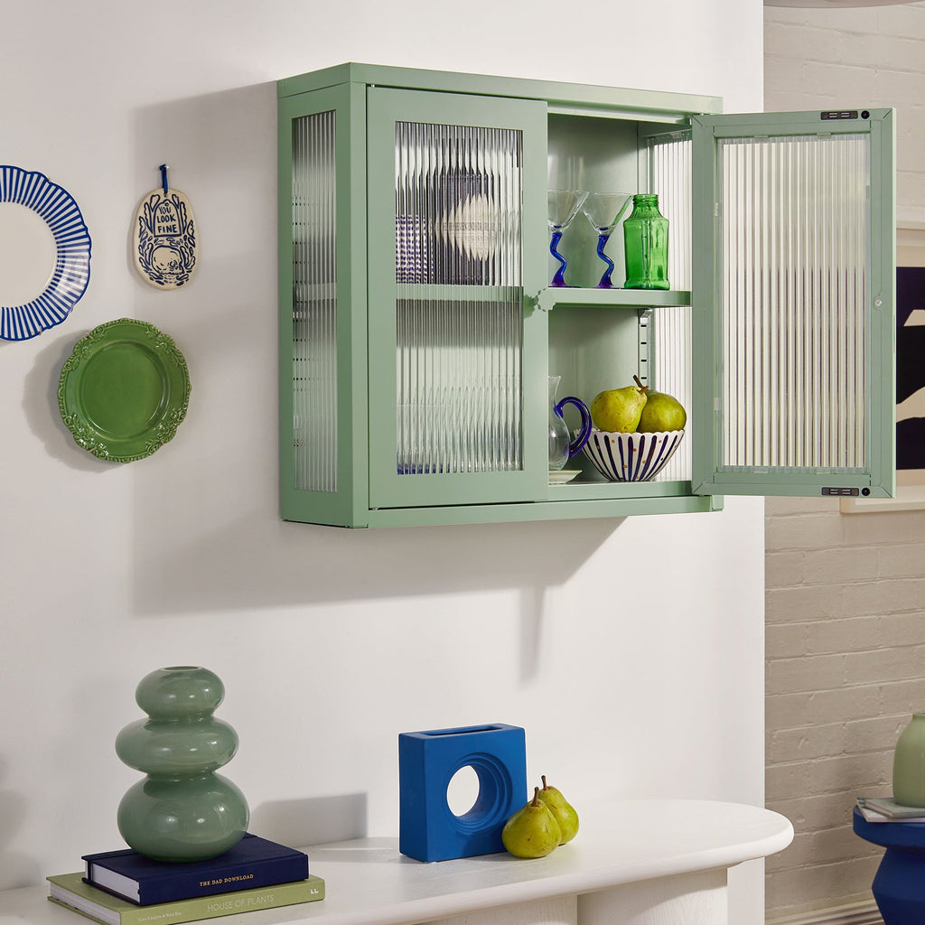 Green wall-mounted cabinet with glass doors in a kitchen setting