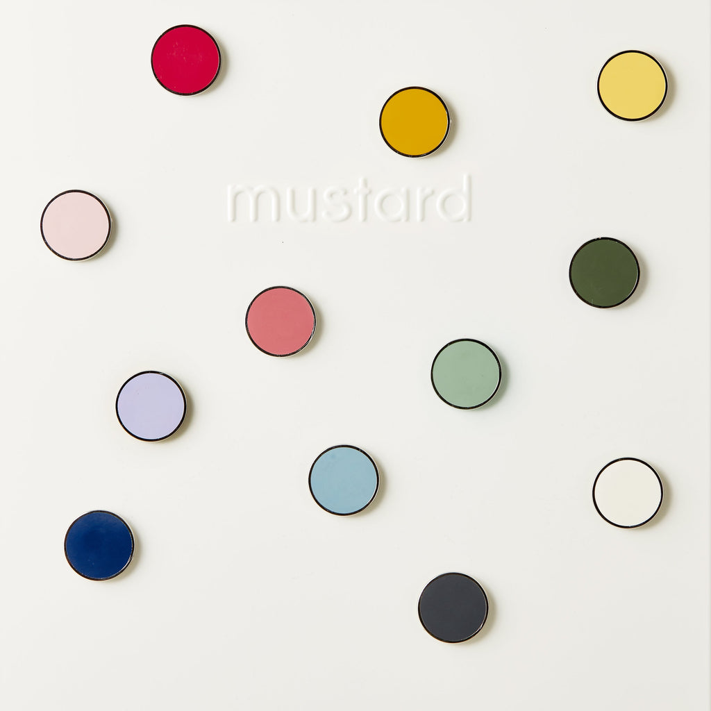 Colourful round magnets on a white background with 'mustard' branding.