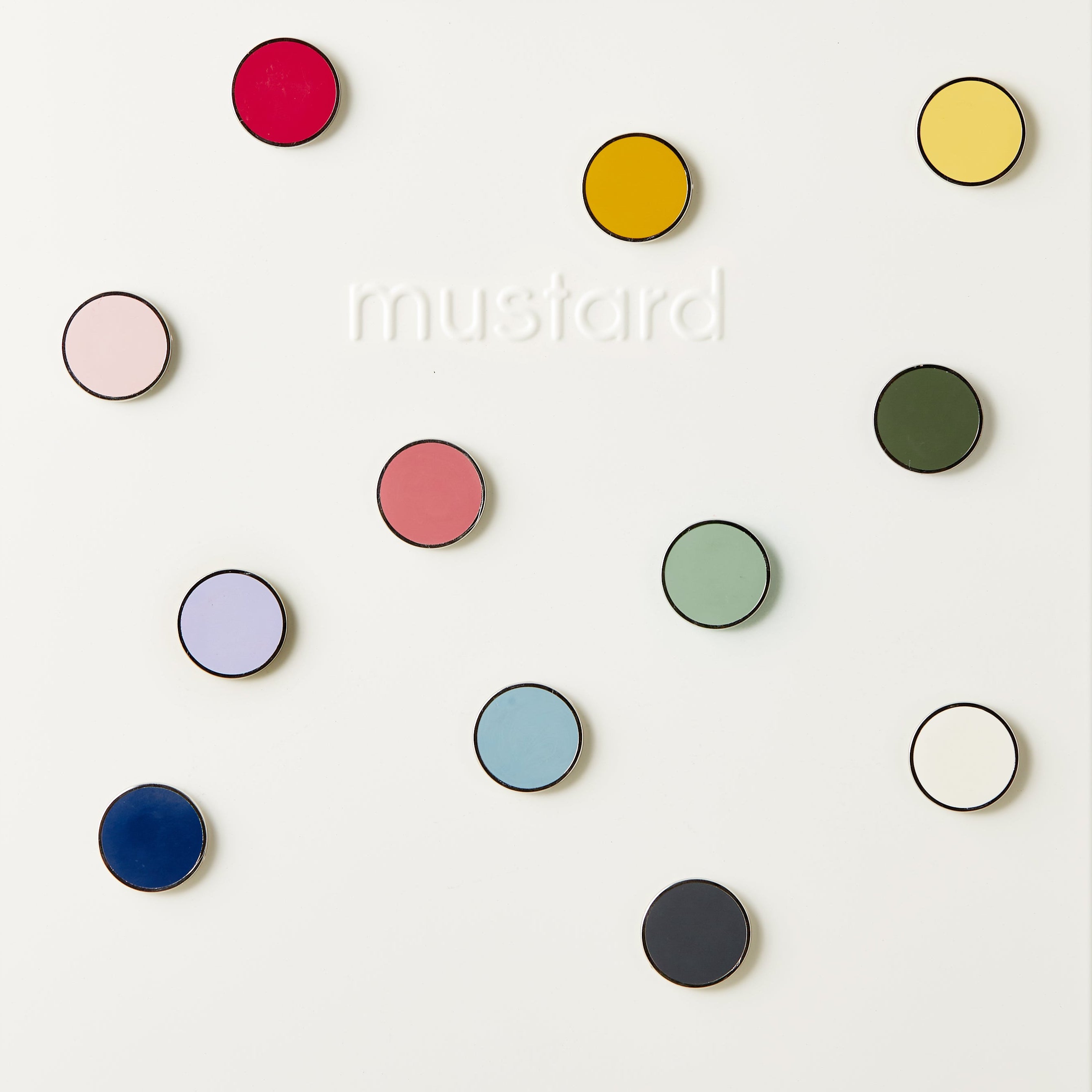 Colourful round magnets on a white background with 'mustard' branding.