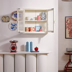 Wall-mounted cabinet with decorative items and a small table with a red apple and blue candlesticks.