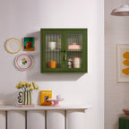 Green cabinet on a white wall with decorative items in a room.