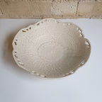 White ceramic bowl on a white surface with a brick wall background