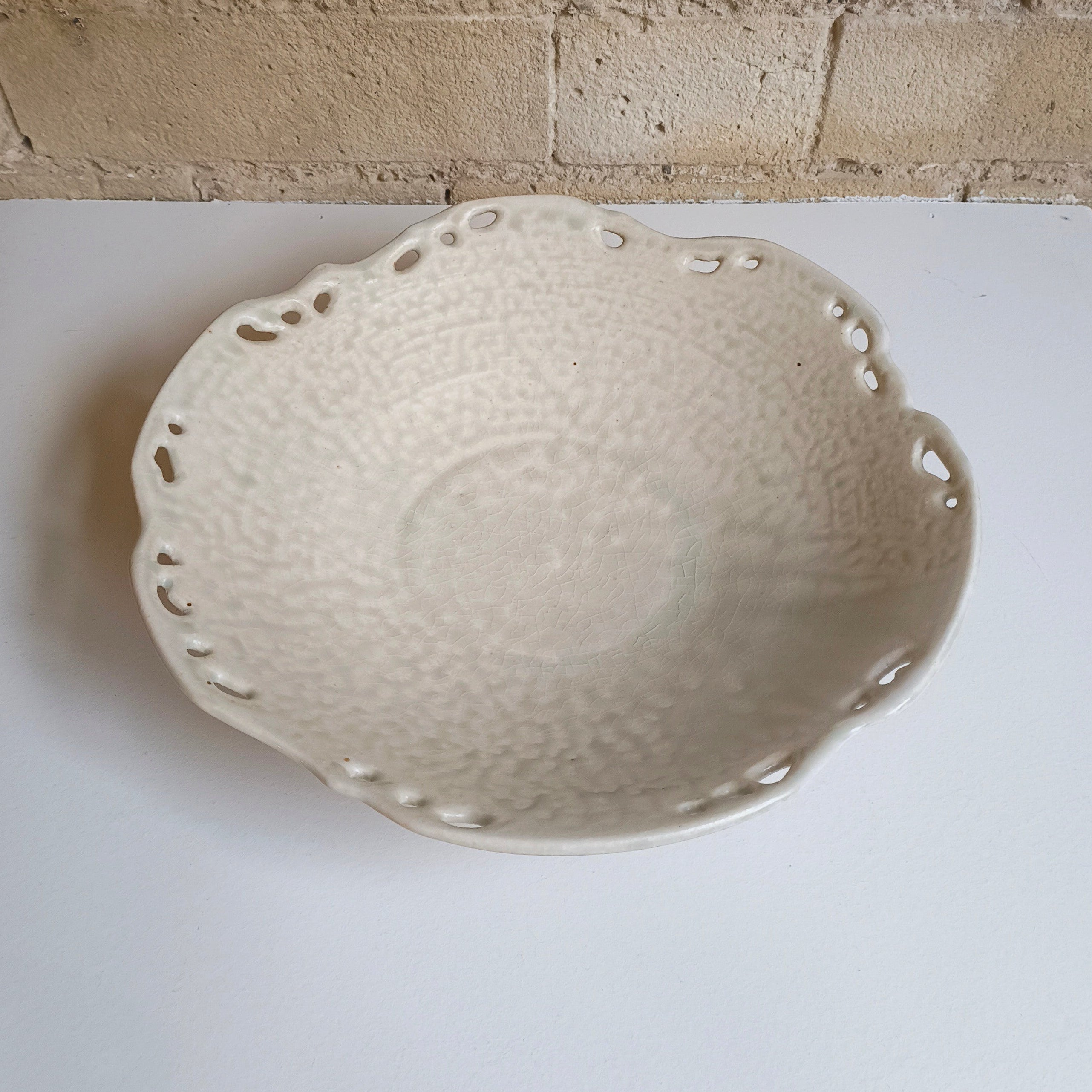 White ceramic bowl on a white surface with a brick wall background