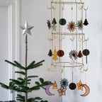 Decorative hanging mobile with celestial designs next to a Christmas tree