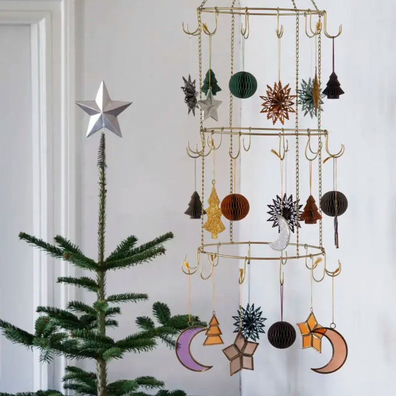 Decorative hanging mobile with celestial designs next to a Christmas tree