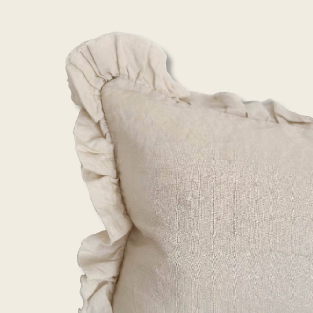 cream cushion with frill edging on a beige background