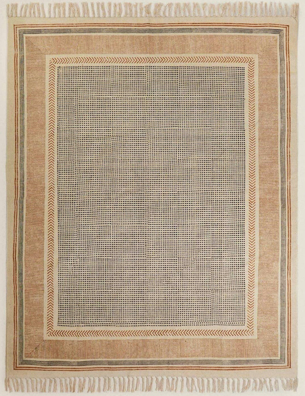 Close-up view of a flatweave rug with a hand-knotted texture, predominantly in a cream color with a rust-colored area, placed on a wooden floor beside a white curtain.