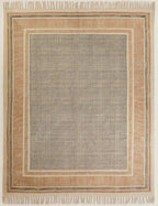 Close-up view of a flatweave rug with a hand-knotted texture, predominantly in a cream color with a rust-colored area, placed on a wooden floor beside a white curtain.