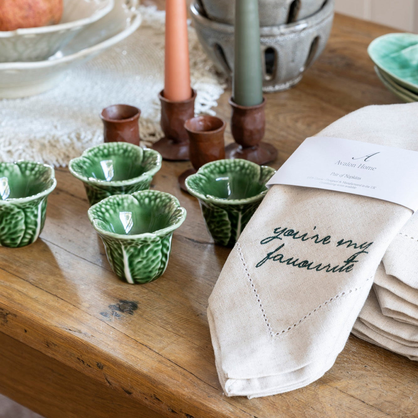 egg cups on a wooden table with candle sticks and a napkin.