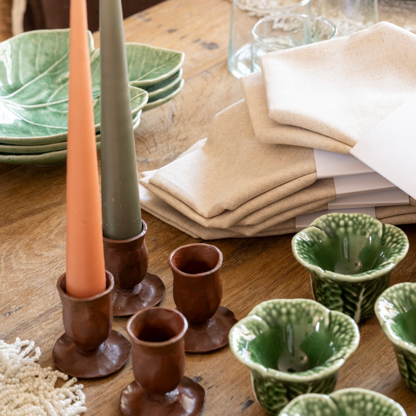 Decorative candles candle holders and egg cups on a wooden table with a rustic setting.