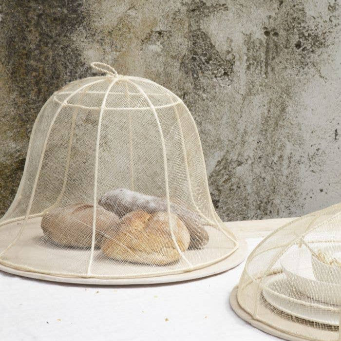 Mesh food covers on a table with a textured wall background