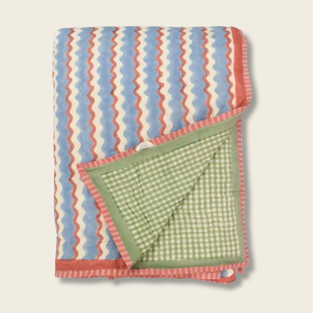 Folded blanket with blue, red, and green pattern on a beige background