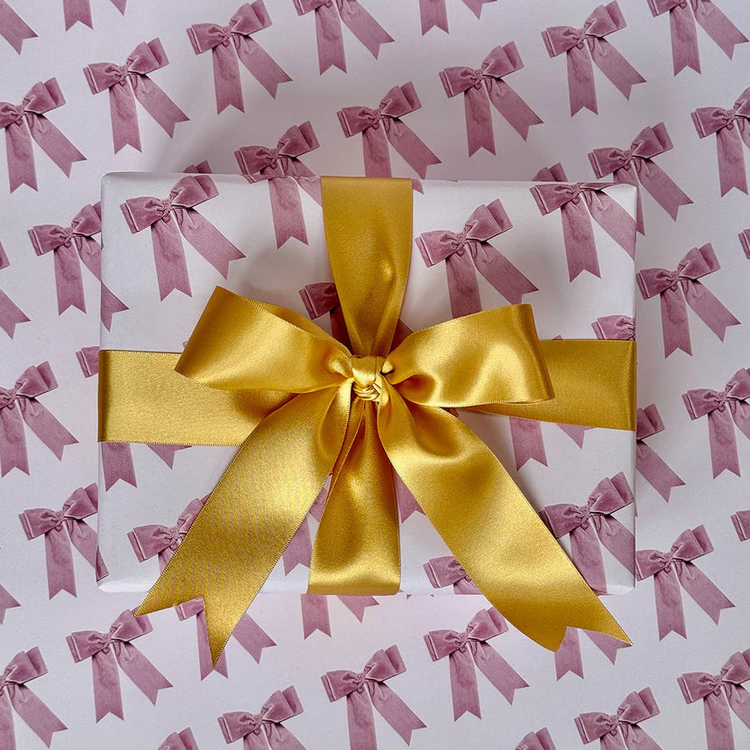 Gift box with a yellow ribbon on a background with pink bows.