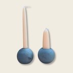 two stone ball candle holders with a long and short stubby candle. 