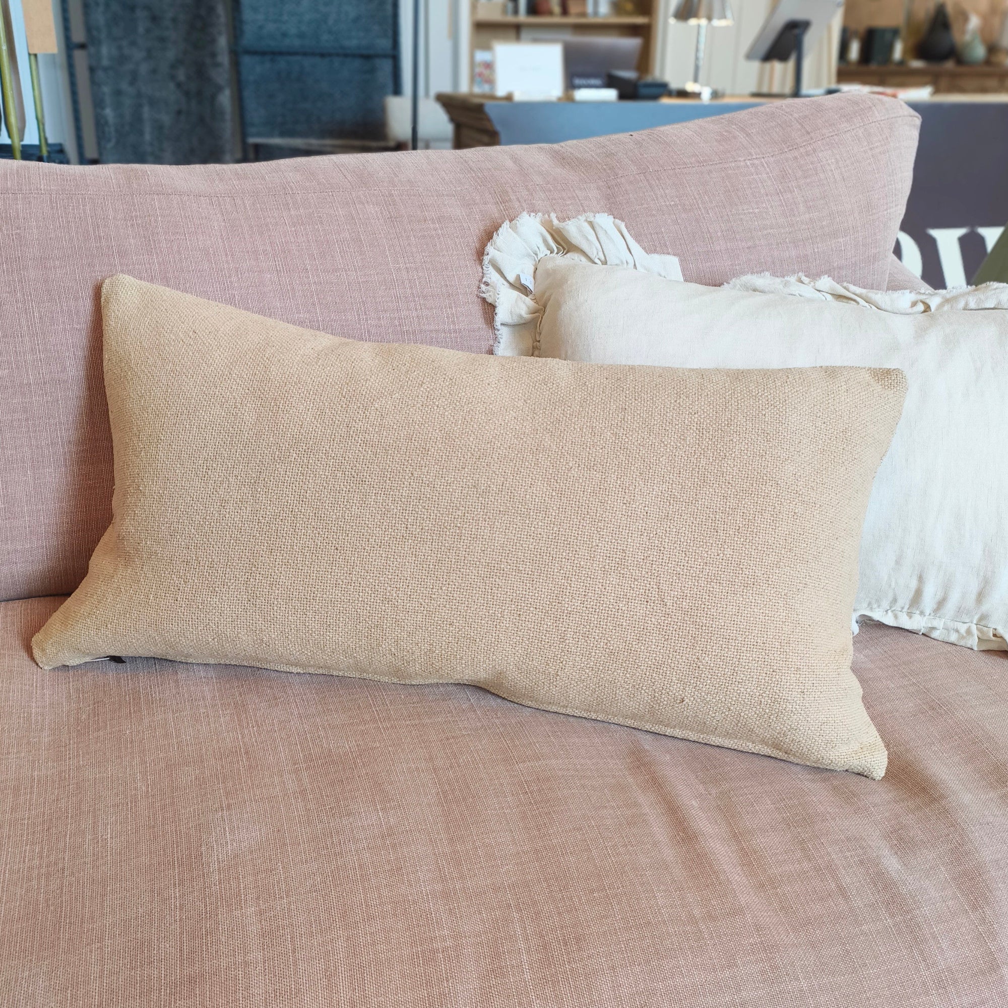 Beige pillow on a brown sofa with a blurred background of a store interior.