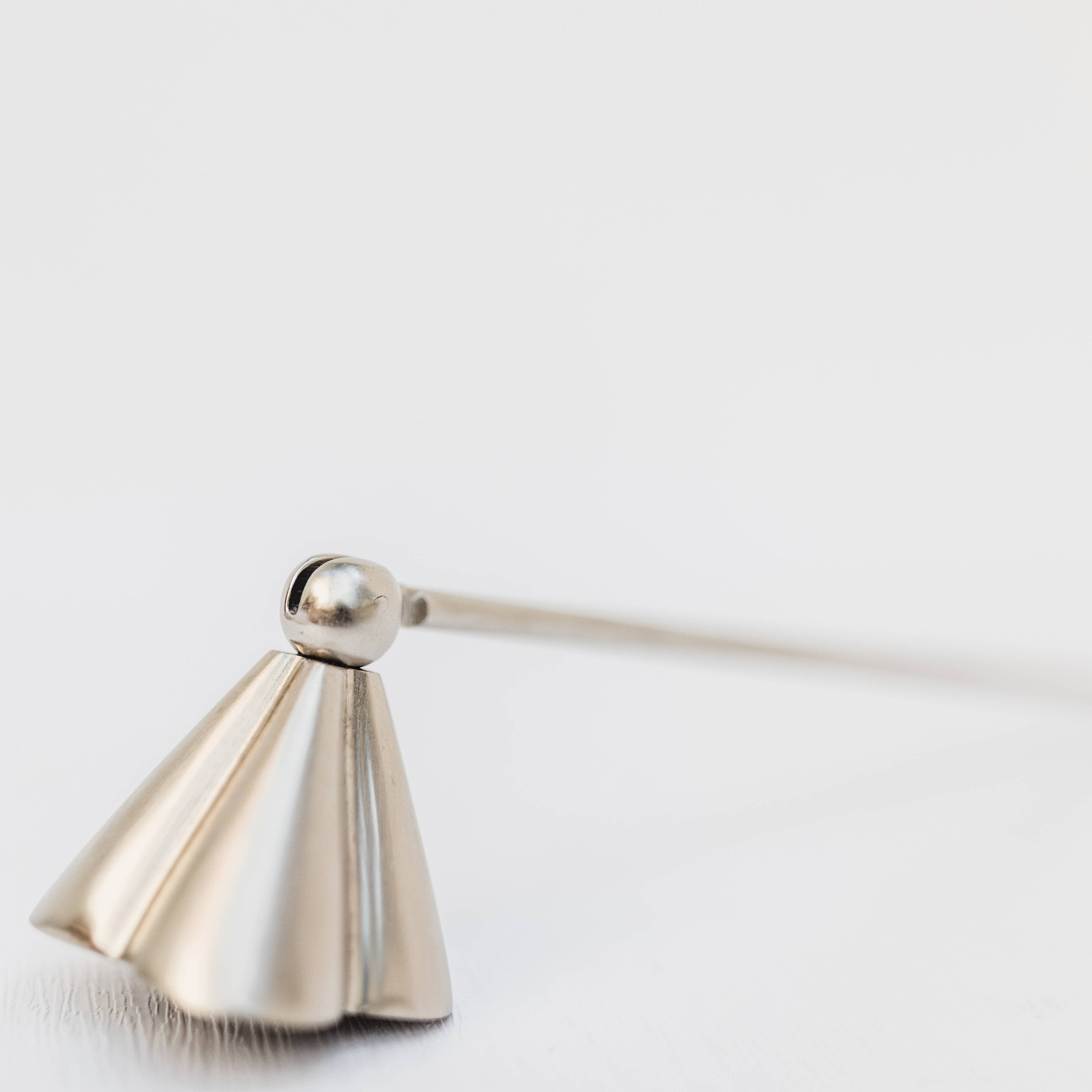 Metallic candle snuffer on a light gray background