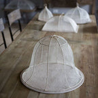White mesh cloche on a wooden table with blurred background