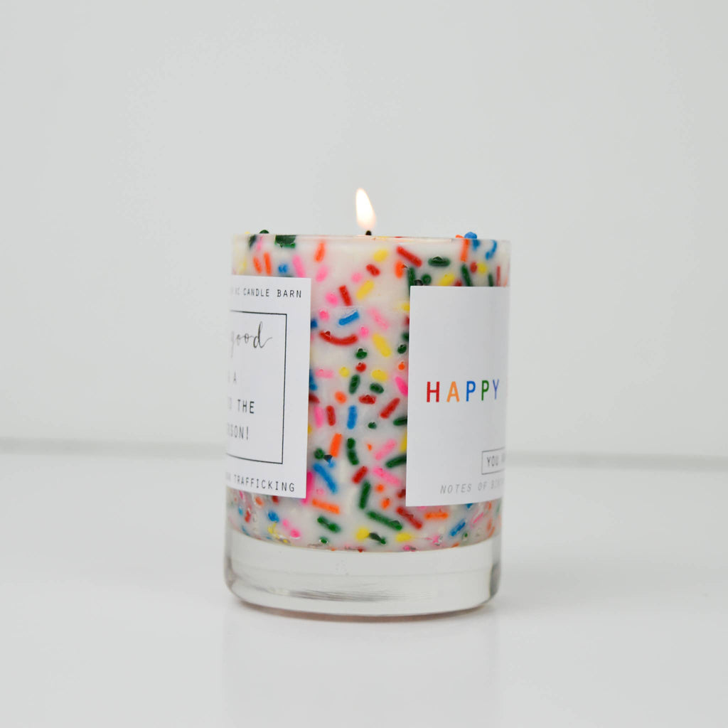 Candle with colorful sprinkles and a 'Happy' label on a white background