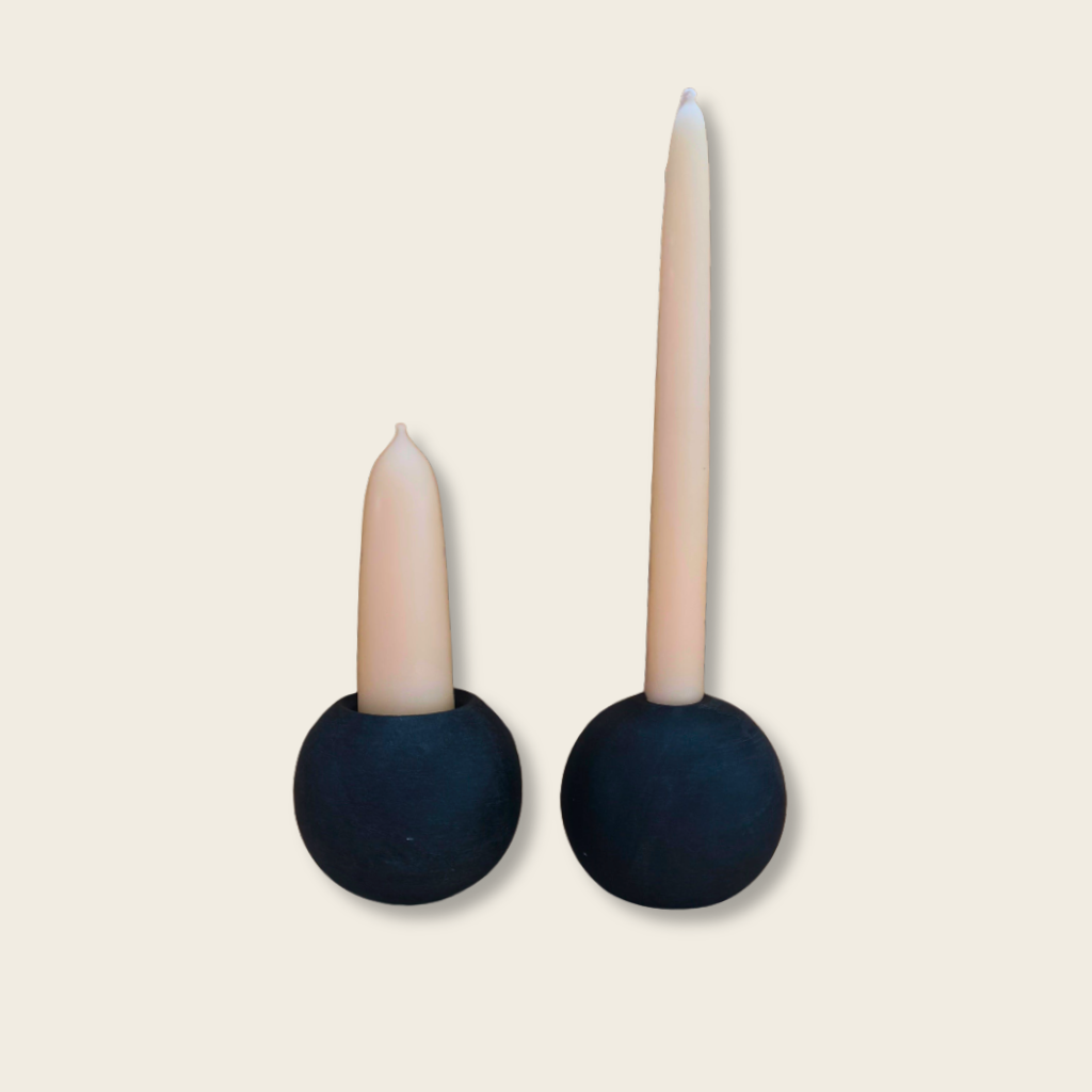 short stubby candle and a tall taper candle in a matching pair of black stone candle holders with a beige background