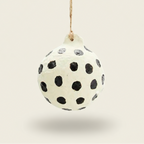 Decorative ball with black polka dots hanging on a white background