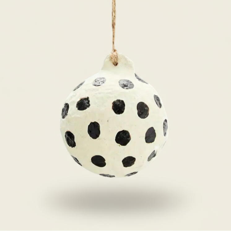 Decorative ball with black polka dots hanging on a white background