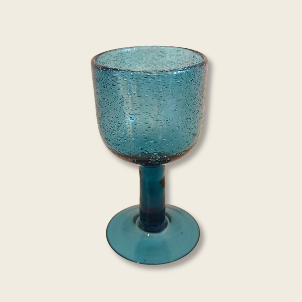 Blue textured glass goblet on a white tiled surface