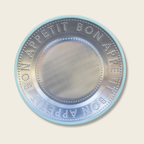 Circular metallic object with embossed text on a beige background