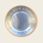 Circular metallic object with text and numbers on a beige background