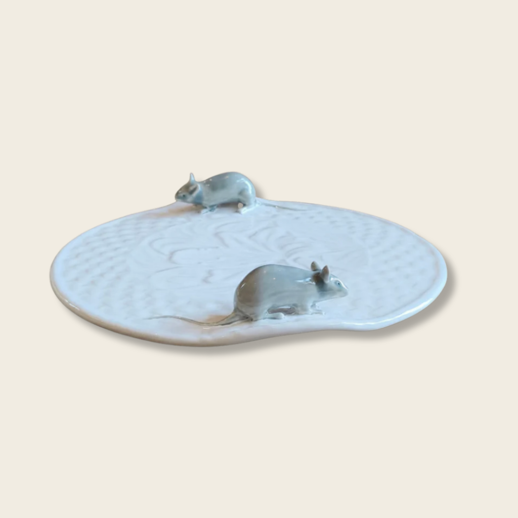 Ceramic dish with two mouse figures on a beige background